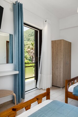 A bedroom with a bed, a wooden wardrobe, a desk, and a balcony with curtains. - The Springfield Corner Apartments by Konnect (Corfu)