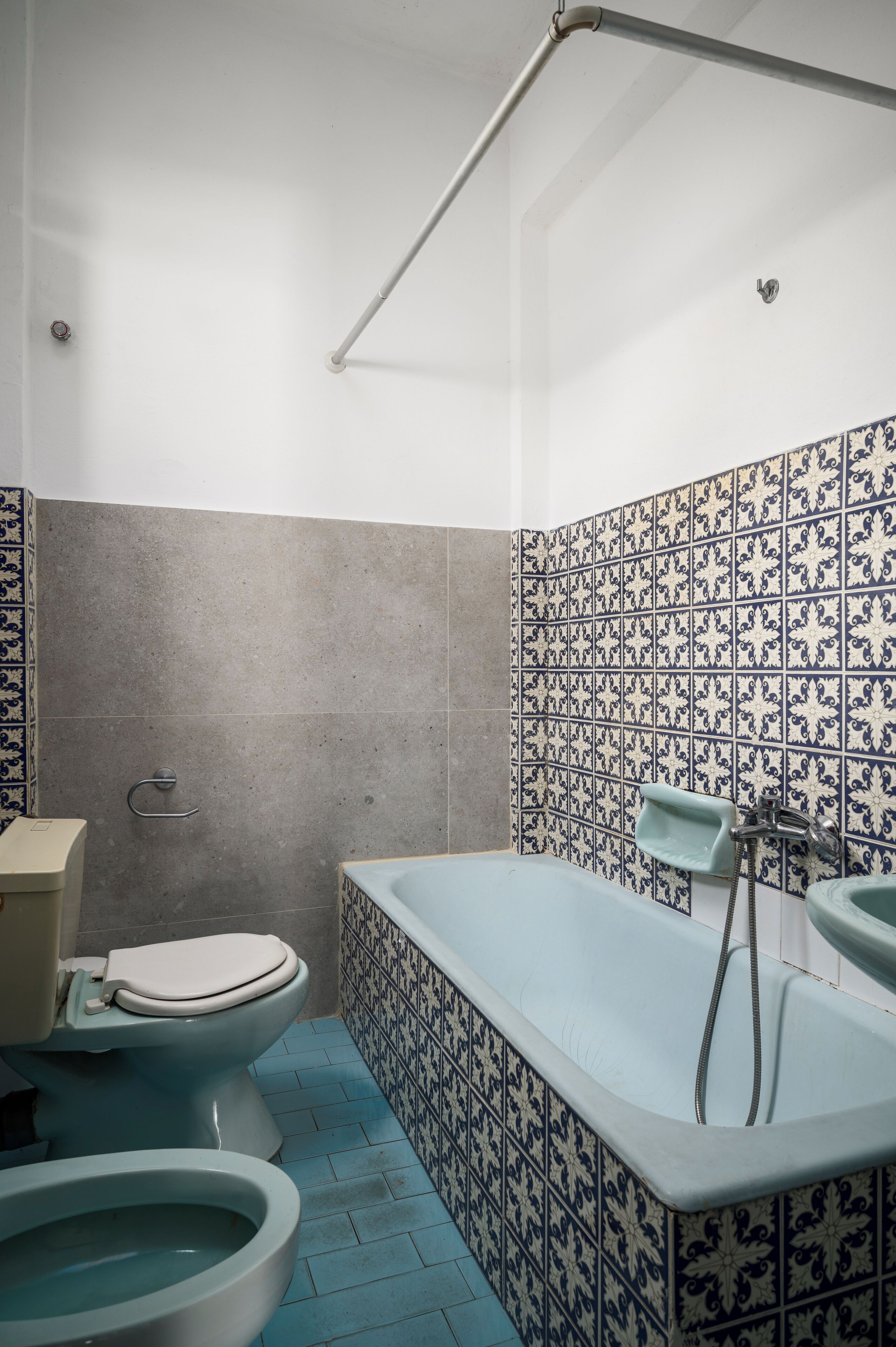 Baño con inodoro, bidé, bañera y paredes con azulejos.