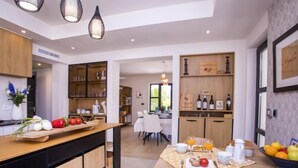 Une cuisine moderne avec des meubles en bois, un îlot central et un coin repas où la table est mise pour le petit-déjeuner.