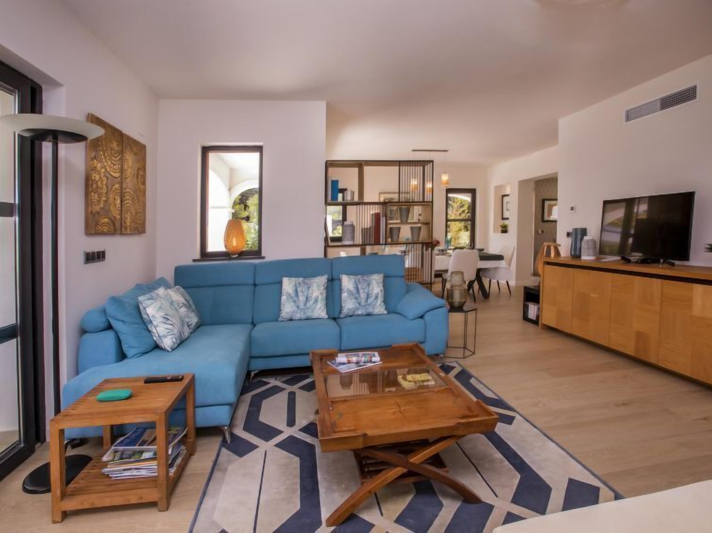 A modern living room with a blue sofa, wooden coffee table, and a bookshelf.
