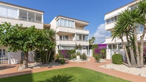 A modern multi-story hotel with balconies, a central courtyard with palm trees, and a well-maintained lawn. - Cala Gabriel by Interhome (Vinarós)