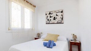 A bedroom with a bed, two bedside tables, a window with curtains, and a wall-mounted artwork. - Cala Gabriel by Interhome (Vinarós)