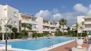 A modern hotel with a swimming pool, multiple balconies, and palm trees. - Cala Gabriel by Interhome (Vinarós)