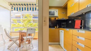 Una cocina pequeña con armarios de madera, una encimera negra y un electrodoméstico rojo.