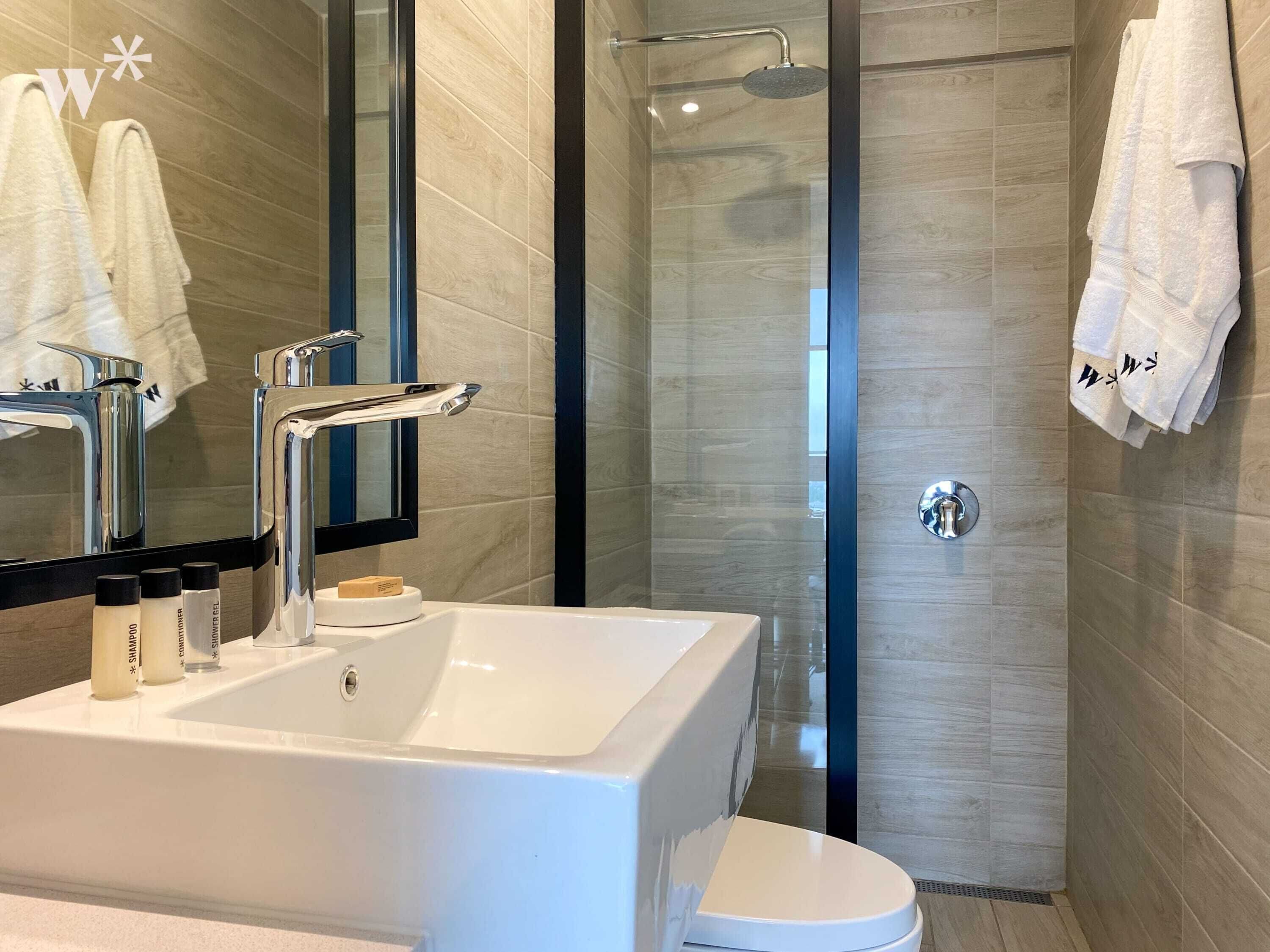 Een moderne badkamer met een groot wastafel, spiegel en douche.