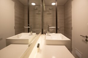 Ein modernes Badezimmer mit zwei Waschbecken, einem großen Spiegel und einer Dusche.