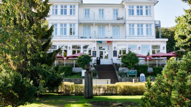 A large, two-story building with a symmetrical facade, multiple windows, and a central entrance with steps leading up to it. - App.11 Zinnowitzer Hof by Interhome (Zinnowitz)