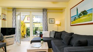 Een woonkamer met een bank, salontafel, televisie en een schilderij aan de muur.