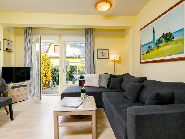 A living room with a sofa, a coffee table, a TV, and a painting on the wall.