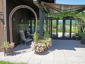 En udendørs terrasse med pergola, siddeområde og krukkeplanter.