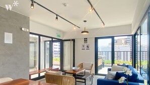 Una habitación de hotel moderna con una mesa de madera, un sofá azul y una pequeña planta en maceta.
