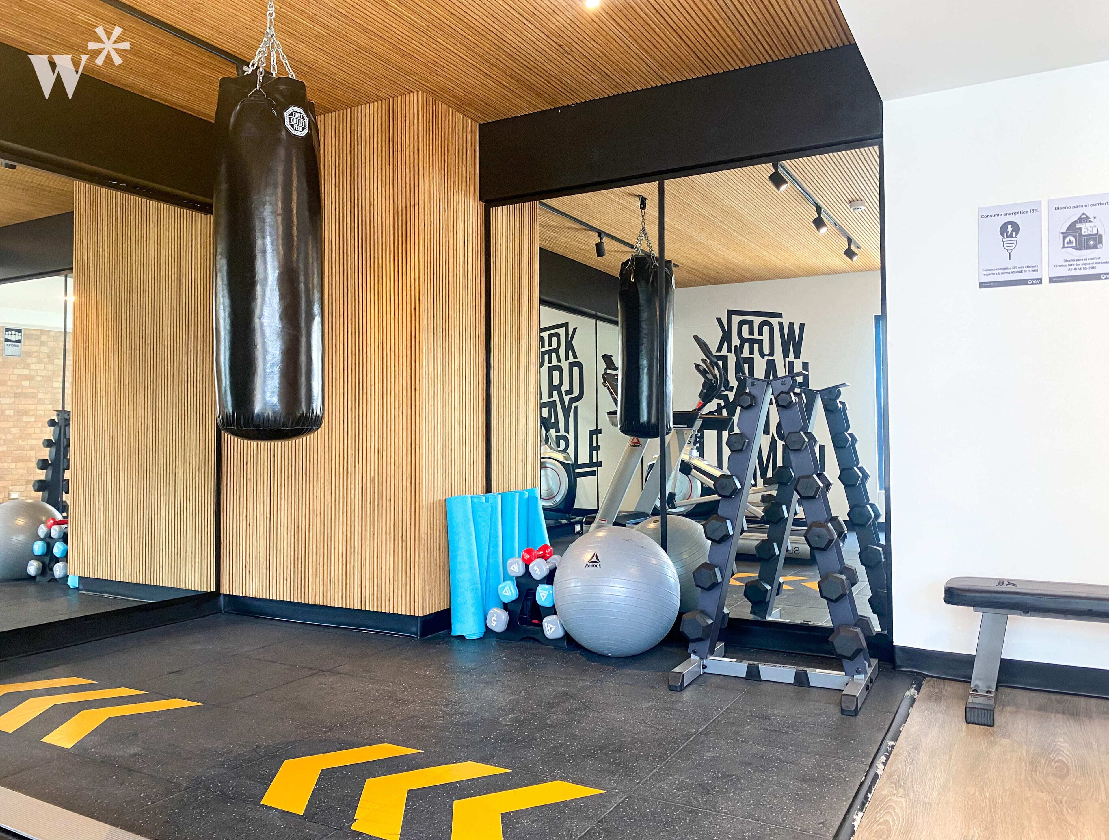 Een sportschool met een bokszak, fitnessballen en gewichthefapparatuur.