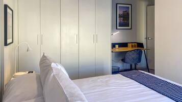 A bedroom with a bed, a desk, and a wardrobe.