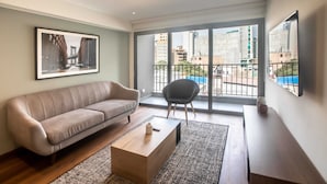 A modern living room with a sofa, coffee table, and a large window with a view of the city.