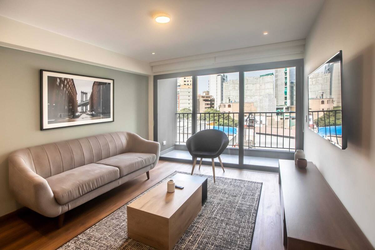 Ein modernes Wohnzimmer mit einer Couch, einem Couchtisch und einem großen Fenster mit Blick auf die Stadt.
