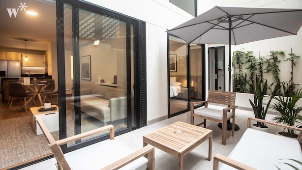 A modern outdoor seating area with wooden furniture and a large umbrella.