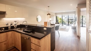 A modern kitchen with wooden cabinets, a black countertop, and a built-in dishwasher.