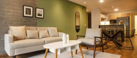 A modern living room with a sofa, a coffee table, and a dining area with chairs and a table.