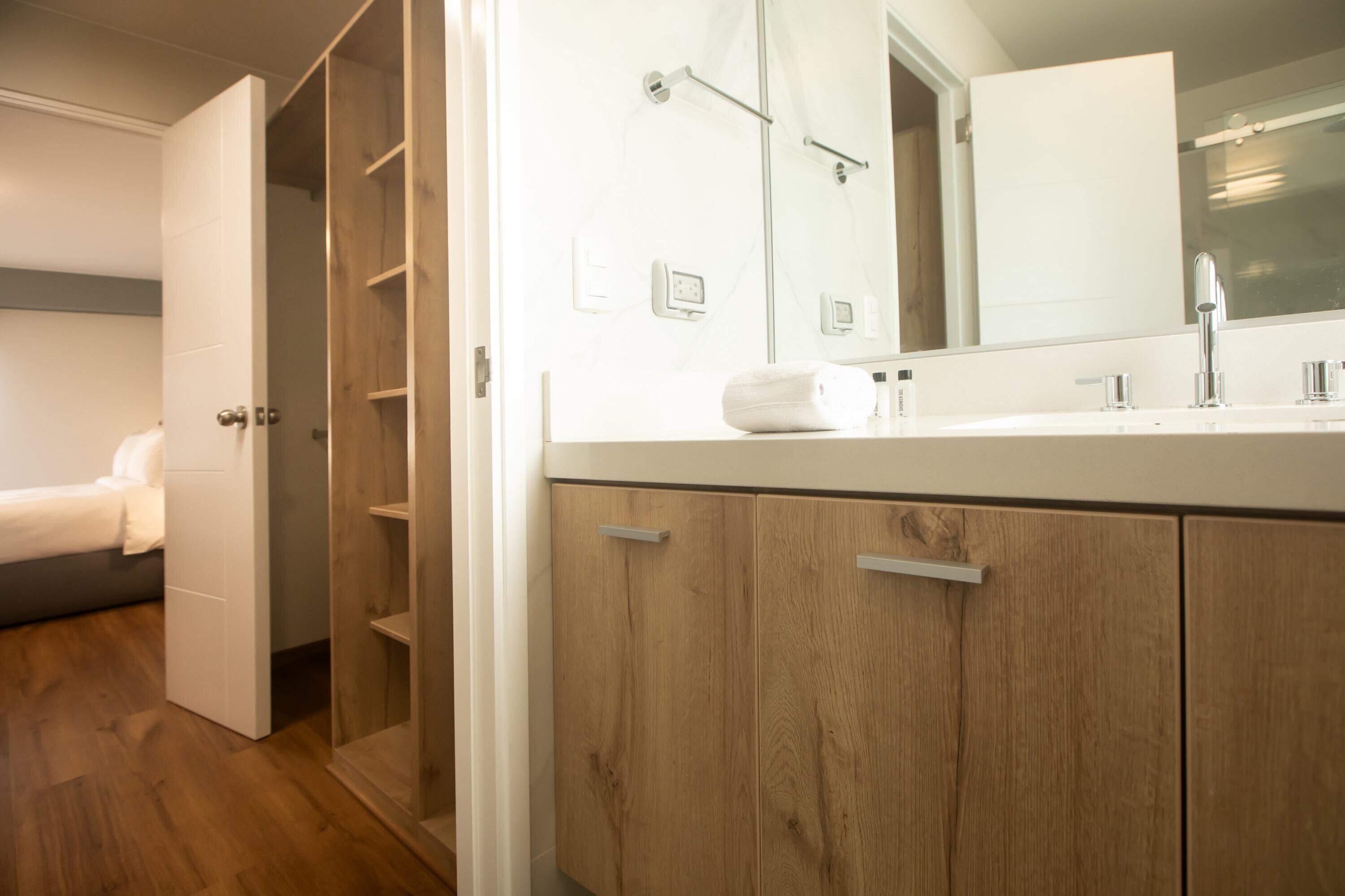 Une salle de bain moderne avec un meuble-lavabo en bois, un grand miroir et un espace douche.
