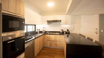 A modern kitchen with wooden cabinets, a Bosch microwave, a dishwasher, and a large island with seating.