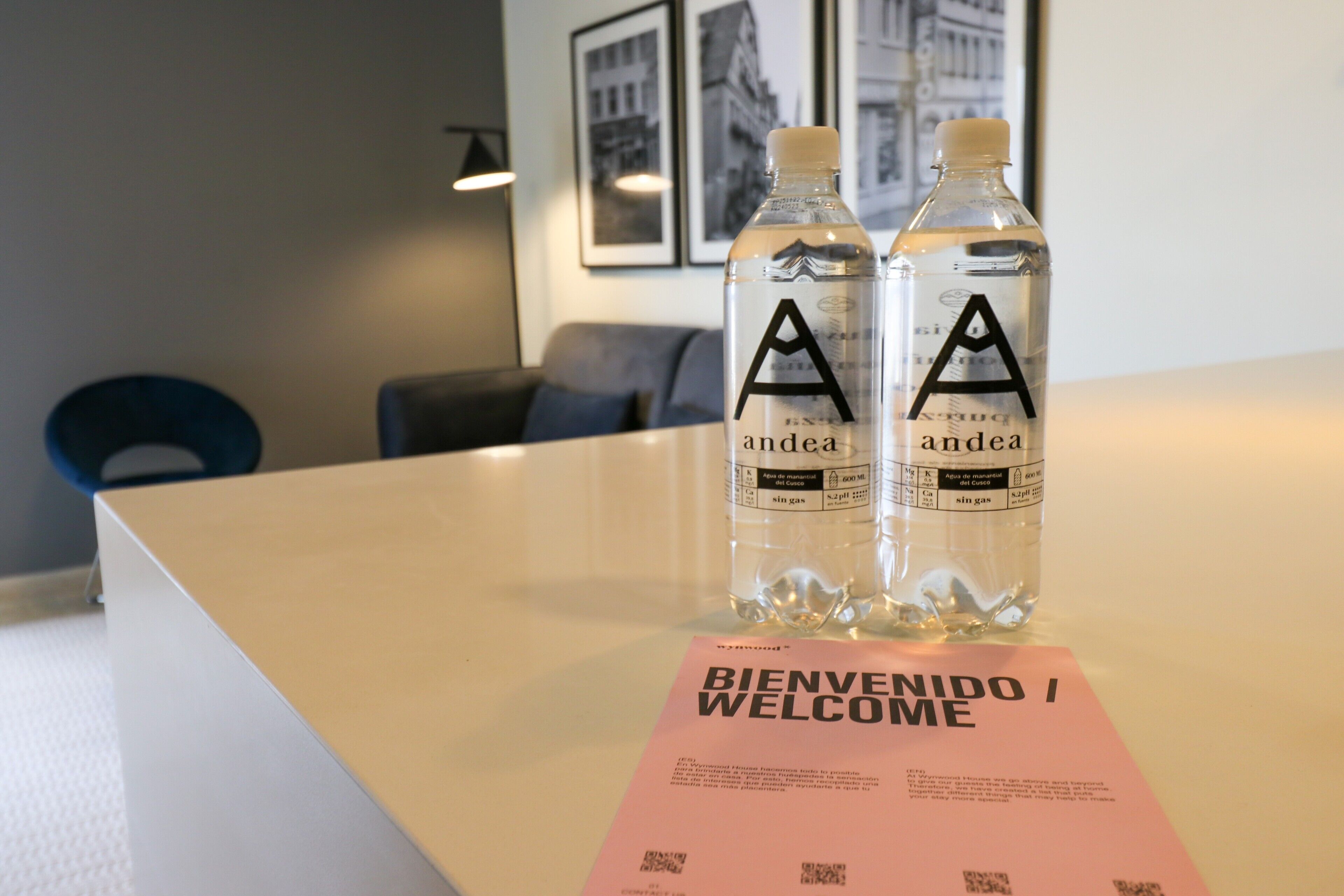 Deux bouteilles d’eau portant l’étiquette « andea » sont posées sur une table, à côté d’une carte sur laquelle est écrit « BIENVENIDO / WELCOME ».