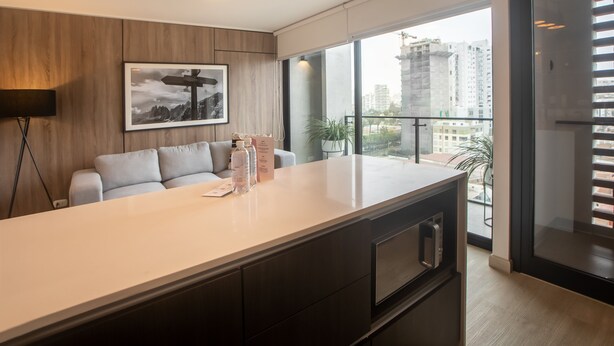A modern kitchen with a large island, a sofa, and a framed picture on the wall. - Wynwood El Sol Este in Barranco (Lima)