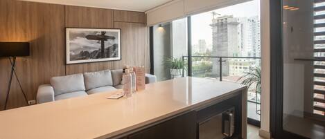 A modern kitchen with a large island, a sofa, and a framed picture on the wall.