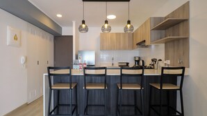 A modern kitchen with a central island, bar stools, pendant lighting, and wooden cabinetry. - Wynwood El Sol Este in Barranco (Lima)