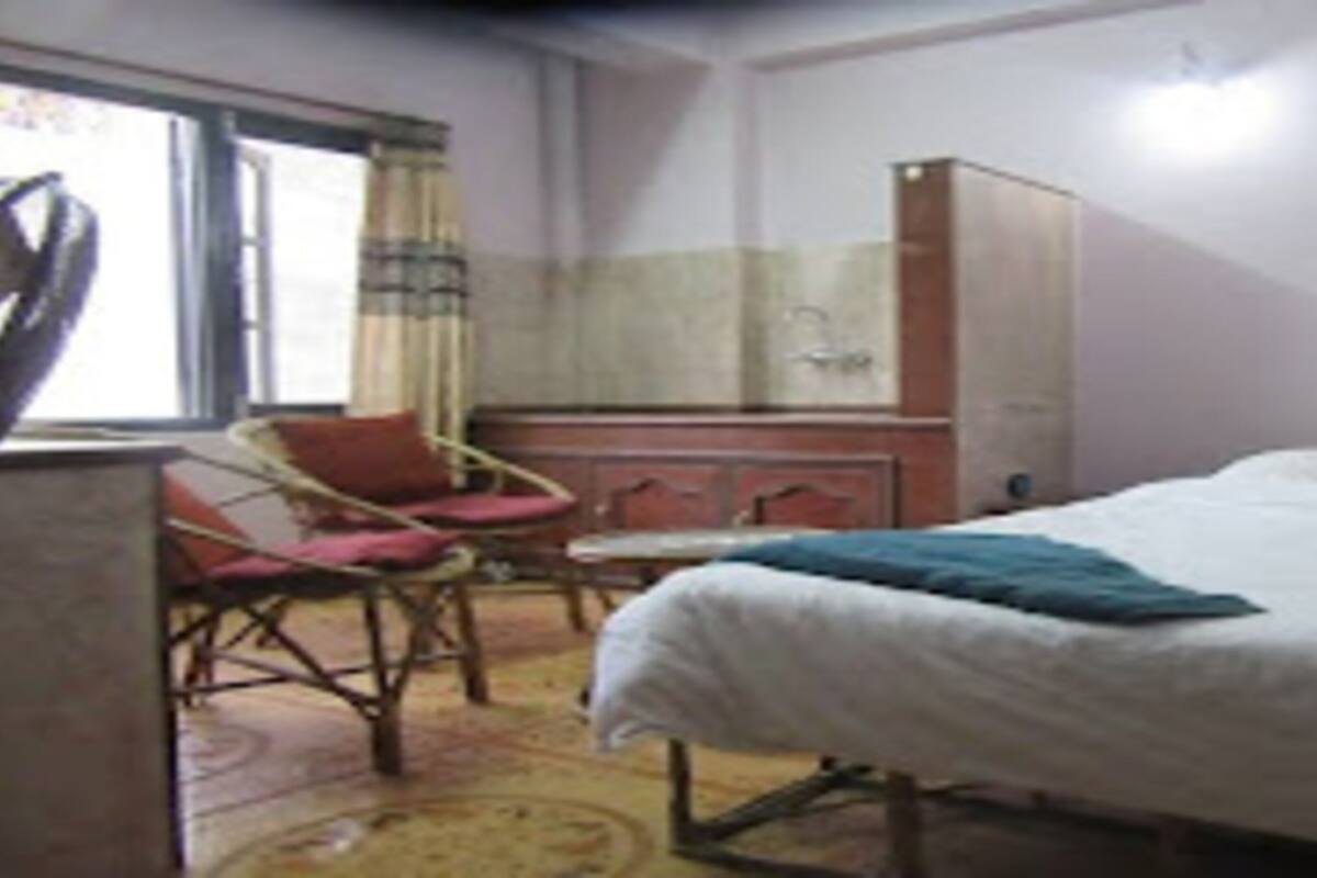 Ein Schlafzimmer mit Bett, Sessel, Kleiderschrank und Fenster.