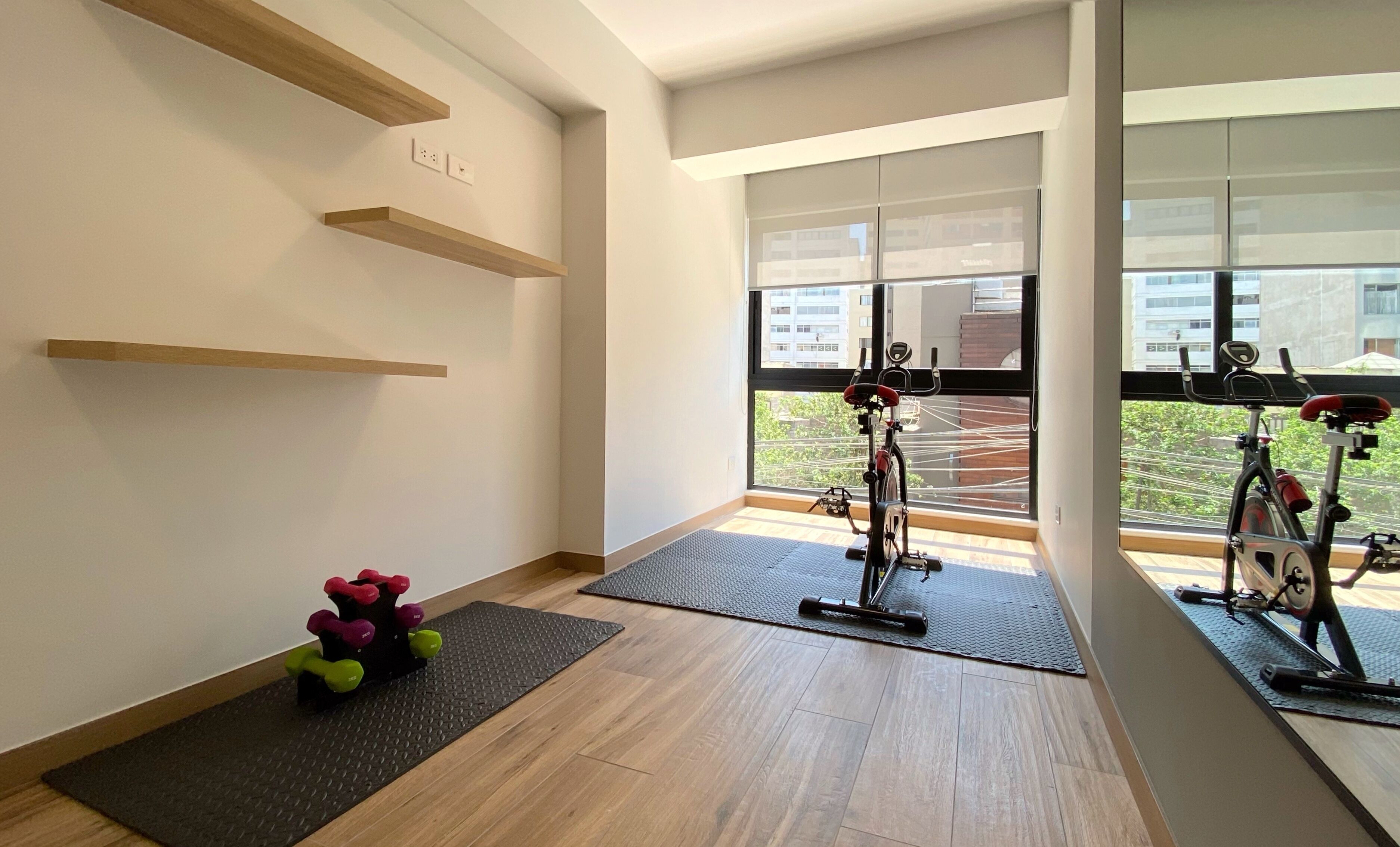 A modern gym with exercise bikes, a yoga mat, and a small set of dumbbells.