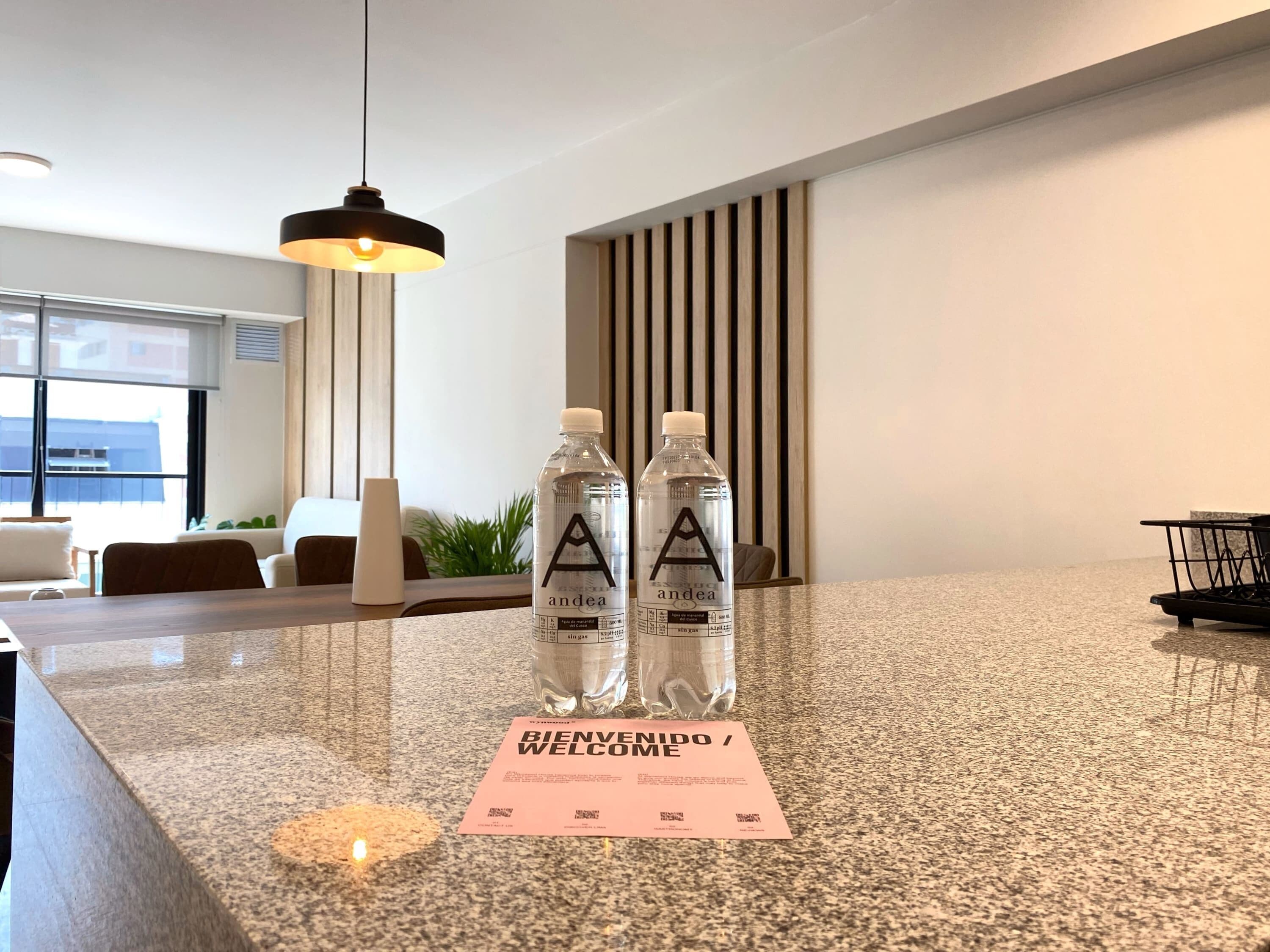 A reception area with a granite counter, two water bottles, and a welcome card.