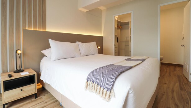 A modern bedroom with a large bed, bedside tables, and a walk-in closet. - Wynwood Colon in Miraflores (Lima)