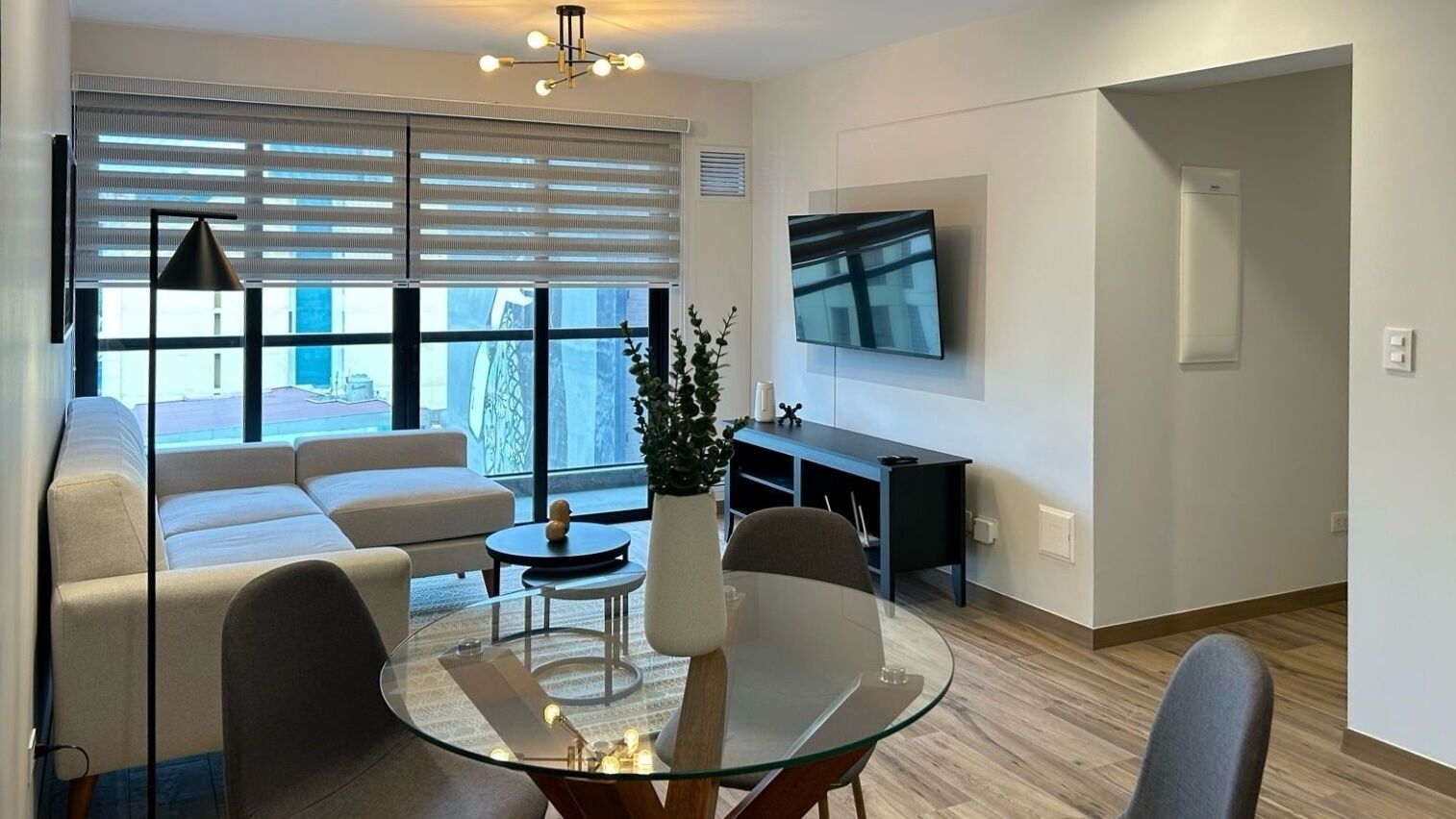 Un salon moderne avec une table basse en verre, un canapé et un téléviseur fixé au mur.