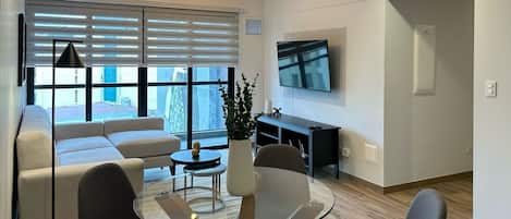 Una sala de estar moderna con una mesa de centro de vidrio, un sofá y un televisor montado en la pared.