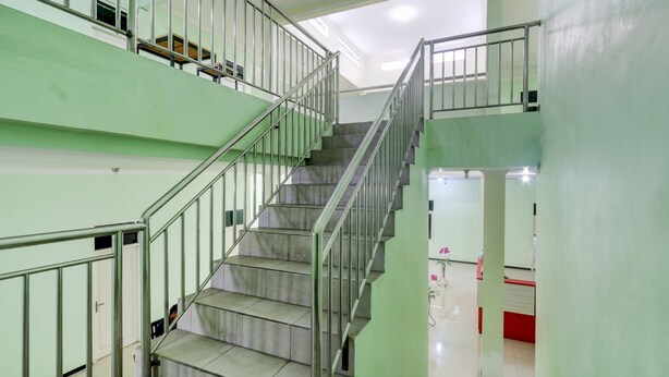 Un interior de varios niveles con escalera, barandales metálicos y una zona de recepción.