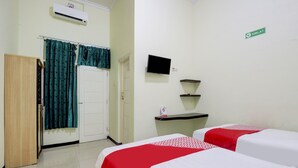 Habitación de hotel con dos camas, un armario, un televisor y un estante pequeño.
