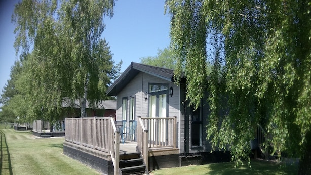 A small cabin with a deck, surrounded by trees. - Cottage in Brookland near Romney Marsh Beach (Fairfield)