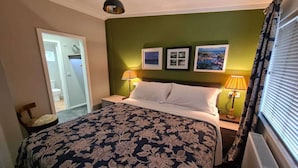 A hotel room with a bed, two bedside lamps, a mirror, and framed pictures on the wall. - Cottage in Brookland near Romney Marsh Beach (Fairfield)