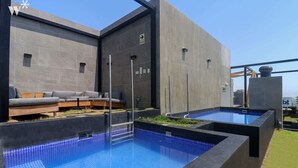 A modern outdoor pool area with a built-in seating area and a clear sky. - Wynwood Dean Valdivia (Lima)