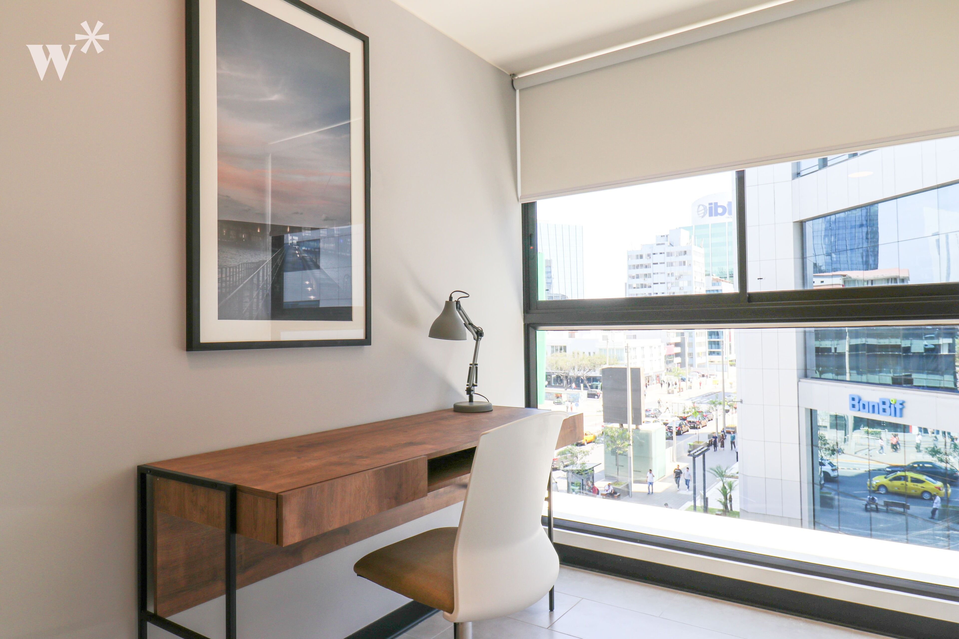 Un espacio de oficina moderno con un escritorio, una silla y un amplio ventanal con vistas a la ciudad.