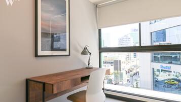 Un espacio de oficina moderno con un escritorio, una silla y un amplio ventanal con vistas a la ciudad.