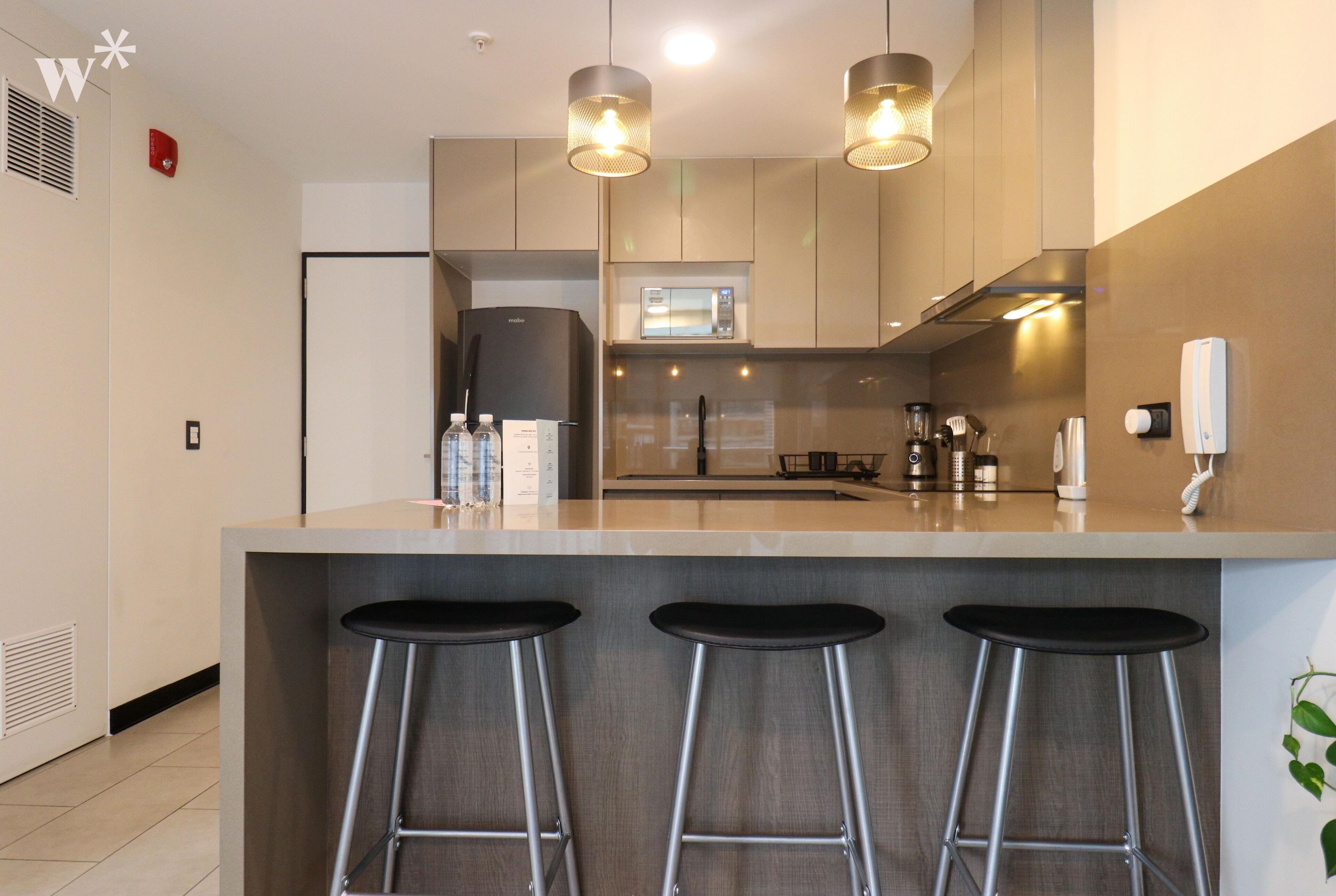 A modern kitchen with a central island, stainless steel appliances, and bar stools.