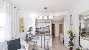 Eine moderne Küche mit weißen Schränken, einer Arbeitsplatte aus Granit und einer zentralen Kochinsel mit Barhocker.