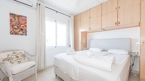 Ein Schlafzimmer mit einem Bett, einem Sessel und einem Bild an der Wand.