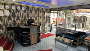 A hotel reception area with a reception desk, a sofa, and a red carpet. - Metropol Hotel 2 (Istanbul)