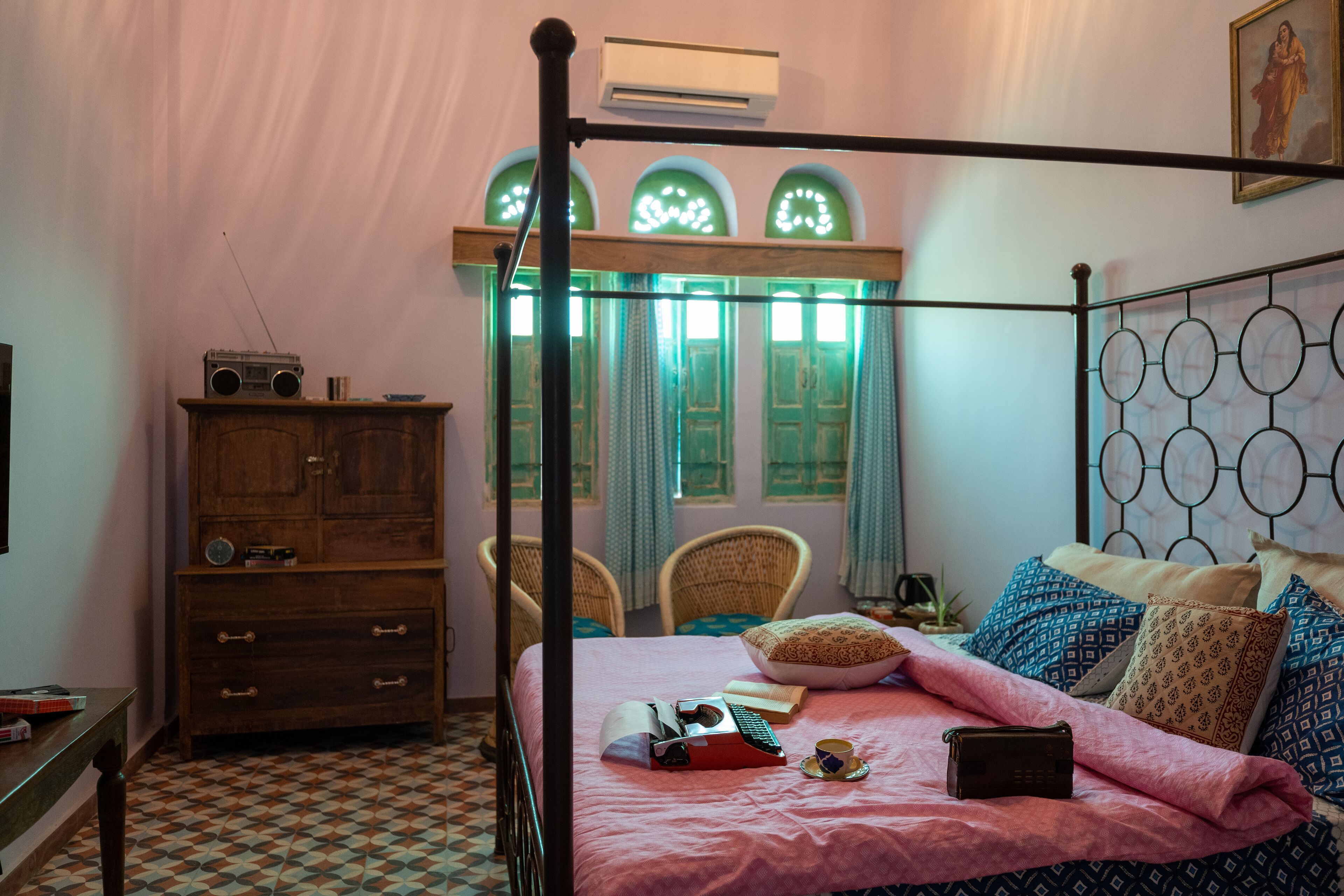 Une chambre à coucher avec un lit à baldaquin, une commode en bois et une fenêtre ornée de rideaux verts.
