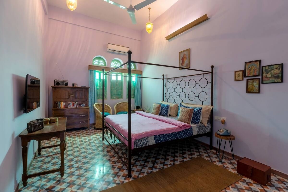 Een slaapkamer met een hemelbed, een houten kast, een tafeltje en een vloer met een patroon.