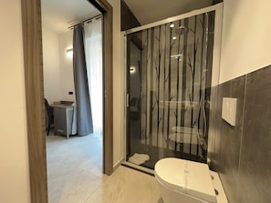 A modern bathroom with a toilet, a glass shower enclosure, and a sink. - Dolmen Guest House (Alghero)