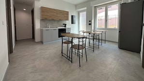 A modern kitchen with a dining area, featuring a built-in oven, a sink, and a window providing natural light. - Dolmen Guest House (Alghero)