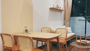 Ett mysigt rum med ett matbord och stolar i trä, en soffa med kuddar, ett litet runt bord och en hylla med dekorativa föremål.
